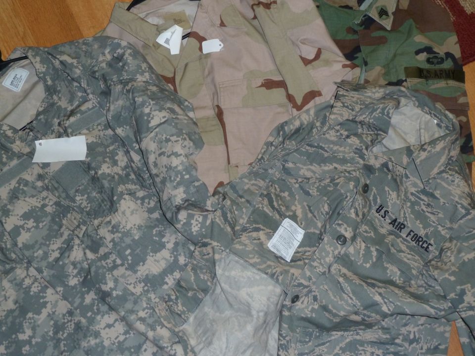 Several military uniforms laid out, including U.S. Air Force and Army digital camouflage patterns