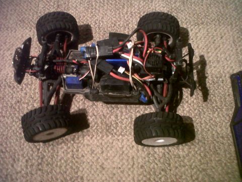 2011 Ford 427 - The underside of a remote control monster truck chassis is shown, revealing its internal components and suspension system.