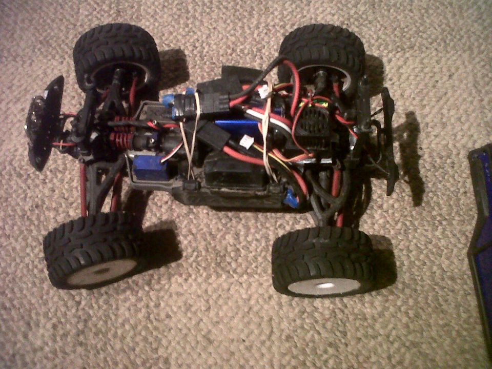 Remote control monster truck chassis with exposed wiring and suspension