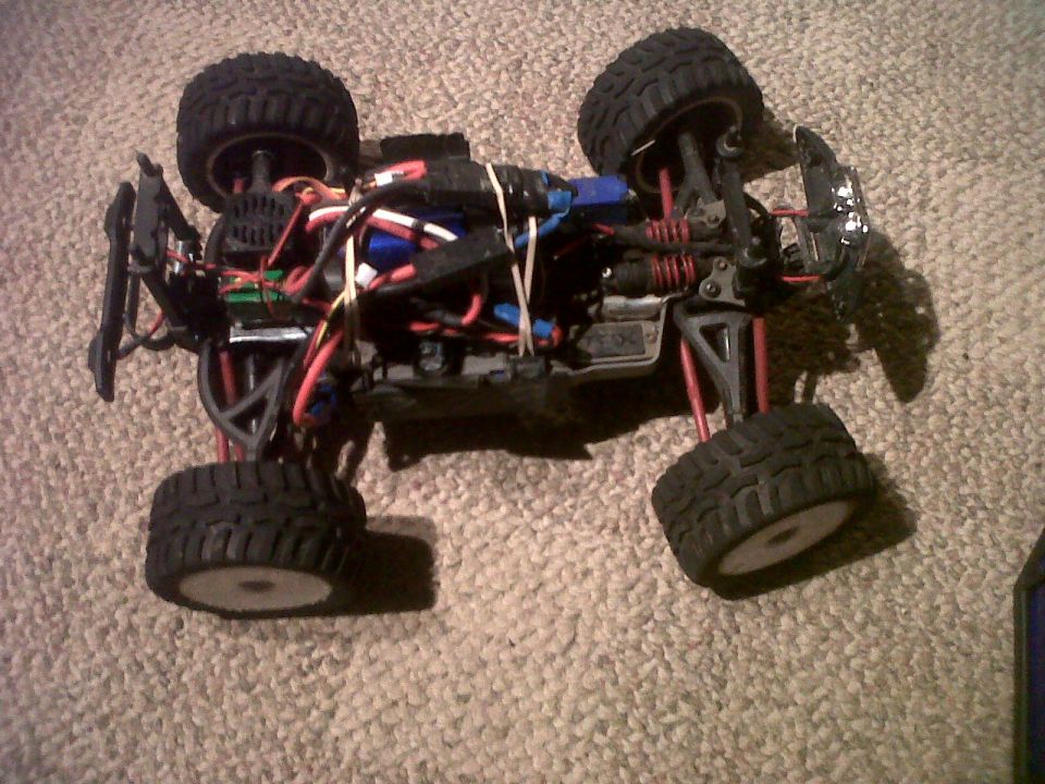 Remote control monster truck chassis with exposed wiring and suspension components