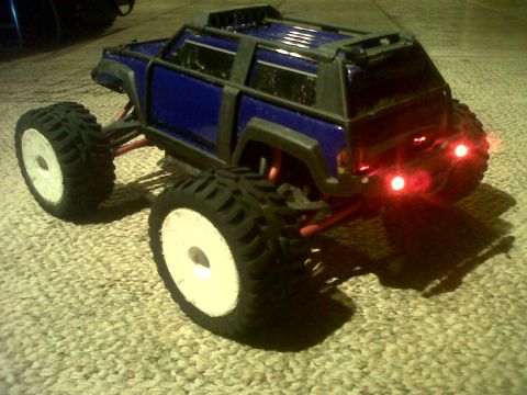 2011 Ford 427 - This remote-controlled truck has a roll cage and oversized wheels, sitting on a carpeted surface.