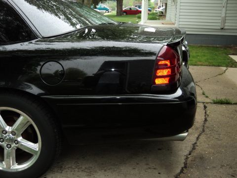 2004 Mercury Grand Marquis - Rear view of a black 2004 Mercury Grand Marquis with a spoiler and chrome exhaust tip.