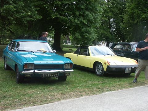 1977 Pontiac Trans Am - A yellow convertible sports car is parked next to a blue sedan and a dark sedan under trees.