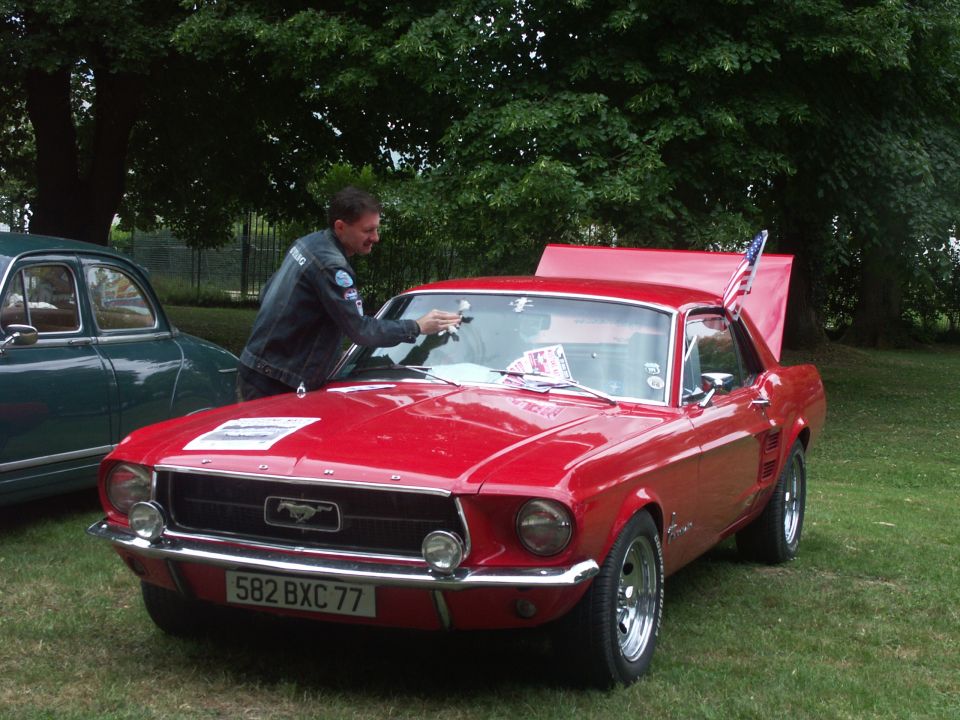 Red 1967 Ford Mustang with hood and trunk open, parked on grass