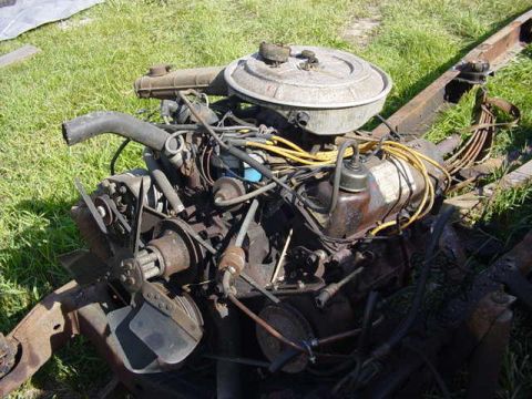 1992 Ford Bronco - Engine assembly, likely removed from a vehicle, sits on a chassis with various hoses and wiring visible.