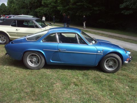 1977 Pontiac Trans Am - A blue coupe is parked on a grassy area with trees in the background and other cars nearby.