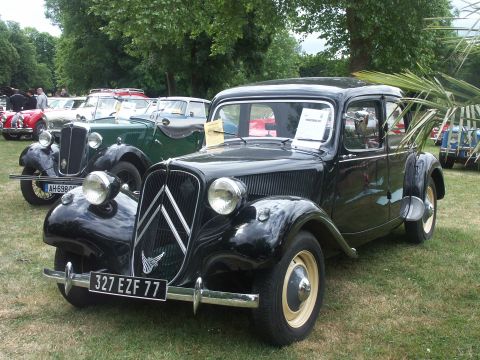 1977 Pontiac Trans Am - A classic black Citroën Traction Avant is displayed at an outdoor event with other vintage vehicles in the background.