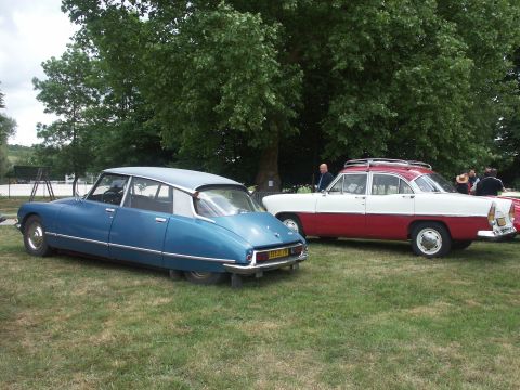 1977 Pontiac Trans Am - Two classic cars, a blue Citroen DS and a two-tone sedan, sit on a grassy field under trees.