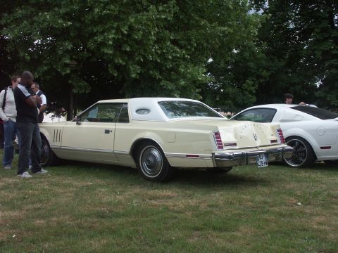 1977 Pontiac Trans Am - A 1977 Lincoln Continental Mark V is parked on grass next to a modern white sports car.