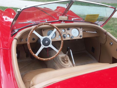 1977 Pontiac Trans Am - Interior of a vintage red sports car, a wood steering wheel and tan seats.