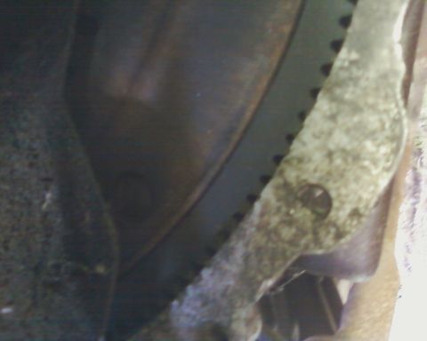 1976 Ford Torino - A close-up view of a mechanical component, possibly from an engine, showing a toothed edge and a bolt hole.