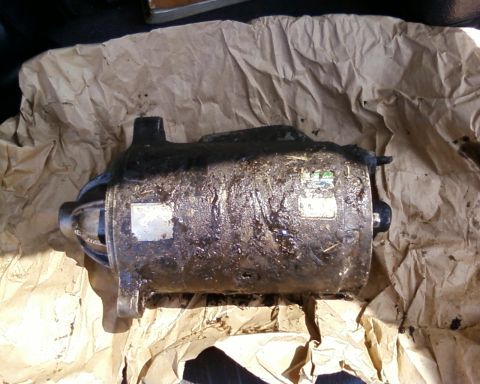 1976 Ford Torino - A greasy starter motor sits on crumpled brown paper, obscuring any vehicle details.