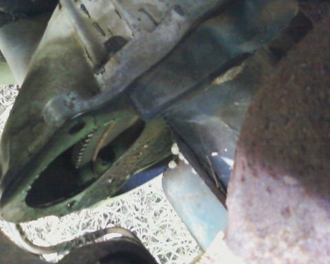 1976 Ford Torino - Close-up view of a starter motor engaging with flywheel teeth on a vehicle's underside.