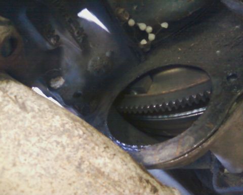 1976 Ford Torino - Close-up view of a starter motor engaging the teeth of a flywheel.