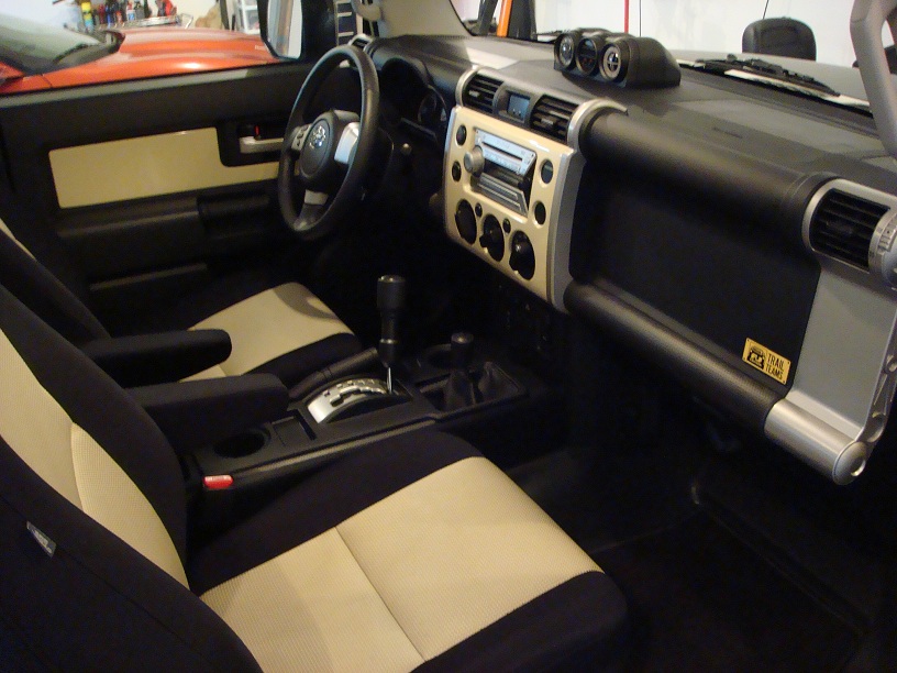 Interior of a Toyota FJ Cruiser, showing the dashboard, seats, and center console. The seats are black and tan