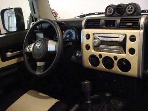 2010 Toyota FJ Cruiser - The interior of a 2010 Toyota FJ Cruiser features a beige dashboard panel surrounding the radio and climate controls.