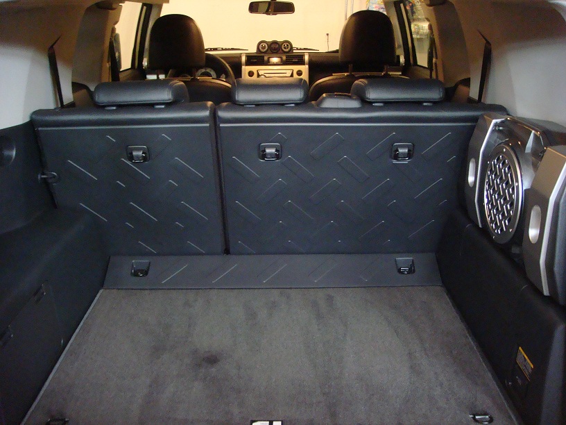 Interior view of a 2010 Toyota FJ Cruiser cargo area, showing folded rear seats and a speaker mounted on the side