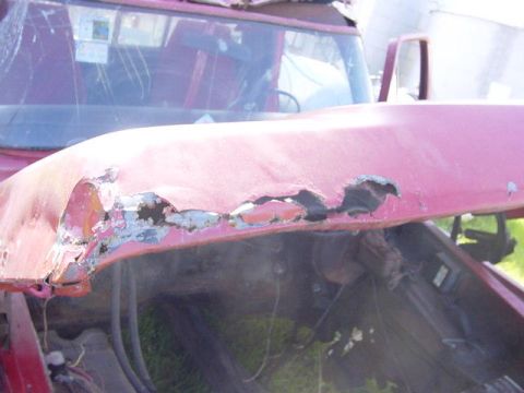 1992 Ford Bronco - The front hood of a red vehicle shows significant rust and damage.
