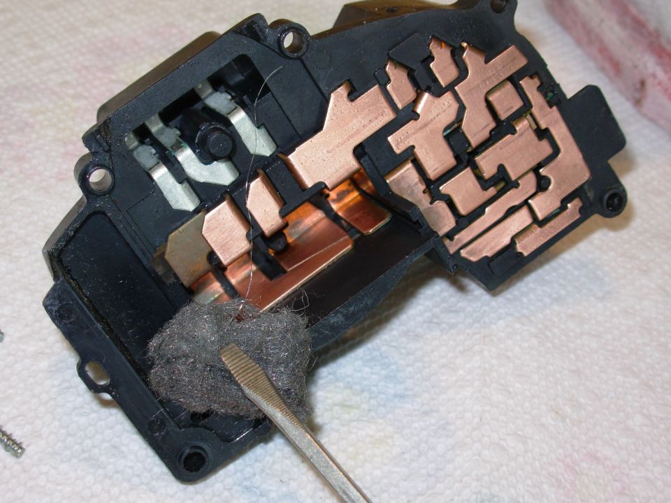 Rinse the contacts with electrical contact cleaner, then polish them with fine steel wool or emery paper.  The headlight slot will be the most difficult, so don't score the contacts with the screwdriver blade.  Use a wood or plastic stick if necessary.

The silver terminals & the 3 copper ones at the L don't need to be cleaned.  If the vehicle doesn't have cornering lights, the top 3 copper ones don't need to be cleaned.