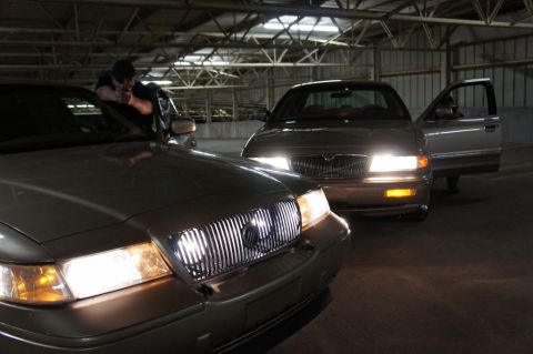 2000 Mercury Grand Marquis - Two 2000 Mercury Grand Marquis sedans are parked in a dimly lit garage, with one car's front end prominently displayed.
