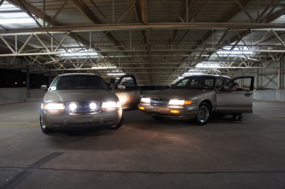 Two tan 2000 Mercury Grand Marquis sedans parked indoors, front view
