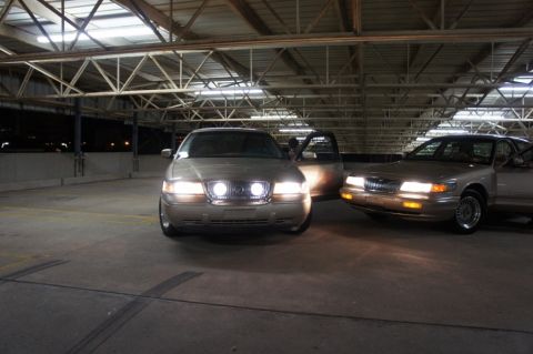 2000 Mercury Grand Marquis - Two Mercury Grand Marquis sedans are parked in a garage, with one car's door open.