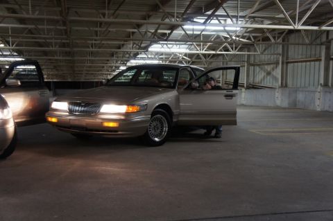 2000 Mercury Grand Marquis - A tan Mercury Grand Marquis is parked in a garage with its driver's side door open.