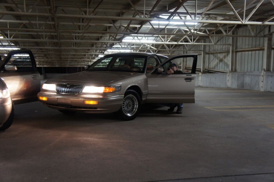 Tan 2000 Mercury Grand Marquis with driver's door open, parked in a garage next to another vehicle