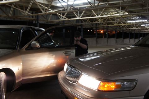 2000 Mercury Grand Marquis - Two 2000 Mercury Grand Marquis sedans are parked closely together inside a building with exposed beams.