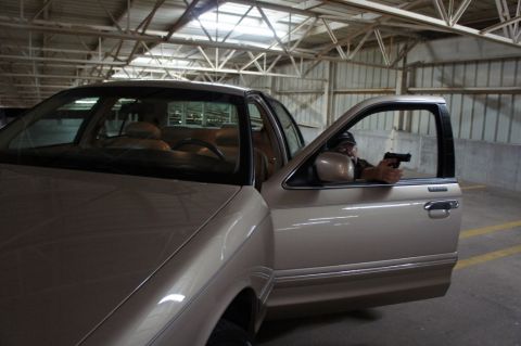 2000 Mercury Grand Marquis - A tan 2000 Mercury Grand Marquis is seen with its driver holding a handgun, parked inside a garage.