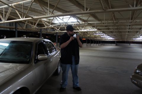 2000 Mercury Grand Marquis - A man stands in a large, empty parking garage, holding a camera near a parked car.