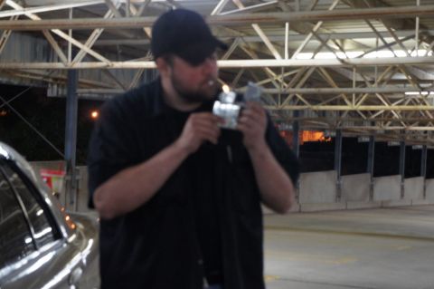 2000 Mercury Grand Marquis - A man lights a cigarette while standing next to a silver vehicle in what appears to be a parking garage.