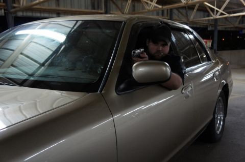 2000 Mercury Grand Marquis - Man with handgun in driver's seat of a 2000 Mercury Grand Marquis.