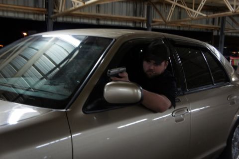 2000 Mercury Grand Marquis - A man is seen holding a handgun while sitting in the driver's seat of a 2000 Mercury Grand Marquis.