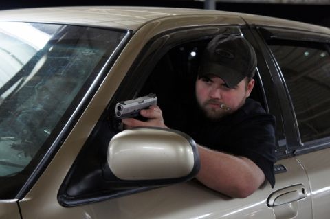 2000 Mercury Grand Marquis - Man holding a handgun while inside a car.