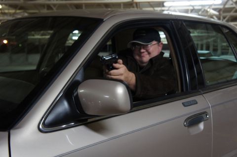 2000 Mercury Grand Marquis - A man points a handgun from the driver's seat of a 2000 Mercury Grand Marquis.