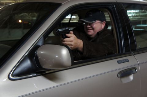 2000 Mercury Grand Marquis - A man inside a vehicle holds a handgun while looking towards the camera.
