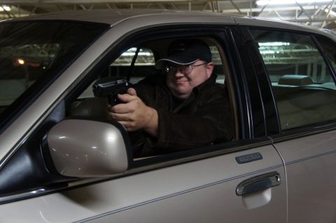 2000 Mercury Grand Marquis - A man holds a handgun while seated in the driver's seat of a 2000 Mercury Grand Marquis.