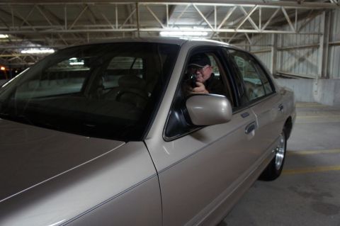 2000 Mercury Grand Marquis - Man points a handgun from the driver's seat of a 2000 Mercury Grand Marquis in a parking garage.