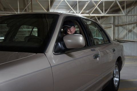 2000 Mercury Grand Marquis - A person is visible inside the driver's side of a tan sedan parked in a garage.