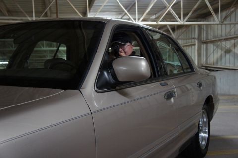 2000 Mercury Grand Marquis - A person peers out the window of a tan 2000 Mercury Grand Marquis sedan parked inside a garage.
