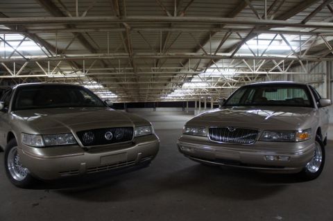 2000 Mercury Grand Marquis - Two tan 2000 Mercury Grand Marquis sedans are parked in a garage, facing each other.