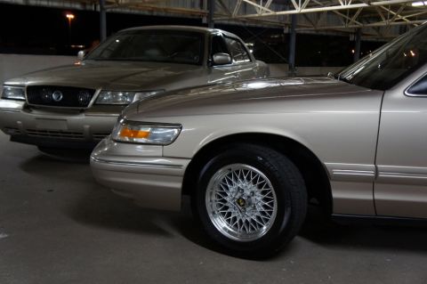 2000 Mercury Grand Marquis - Two tan 2000 Mercury Grand Marquis sedans are parked side-by-side in a garage.