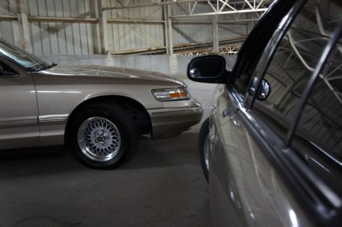 2000 Mercury Grand Marquis - A tan sedan is parked in a garage, with another vehicle partially obscuring the view.