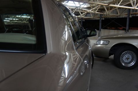 2000 Mercury Grand Marquis - Two sedans parked side-by-side in a garage, one car's rear section and the other's front are visible.