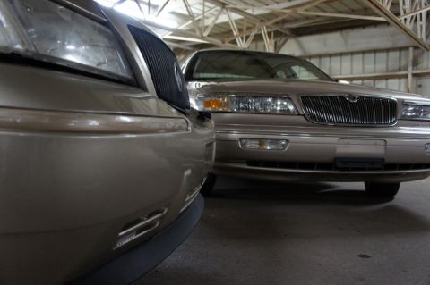 2000 Mercury Grand Marquis - Two tan sedans are parked side-by-side in a garage, with the front of one vehicle prominently featured.
