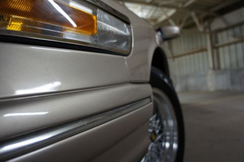 2000 Mercury Grand Marquis - A close-up view of the front corner of a tan 2000 Mercury Grand Marquis, showing the headlight and fender detail.