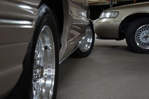 2000 Mercury Grand Marquis - Two cars parked together, one in focus on the left and another on the right showing its front end.