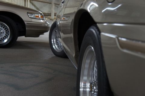 2000 Mercury Grand Marquis - Two sedans are parked side-by-side in an indoor space, showing their profiles and wheels.