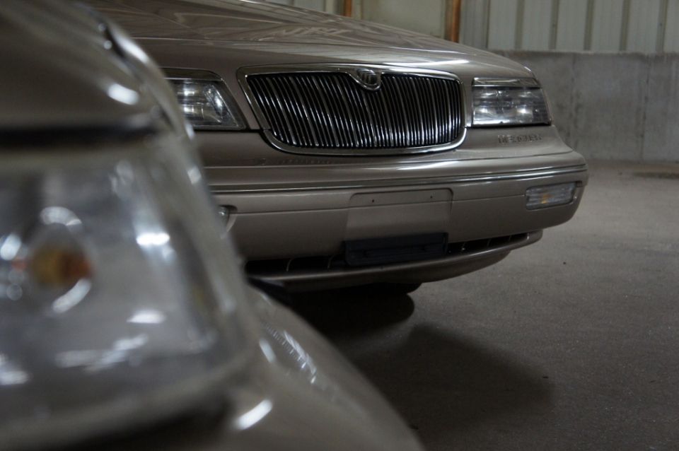 Front of a tan Mercury Grand Marquis with a chrome grille, parked next to another car